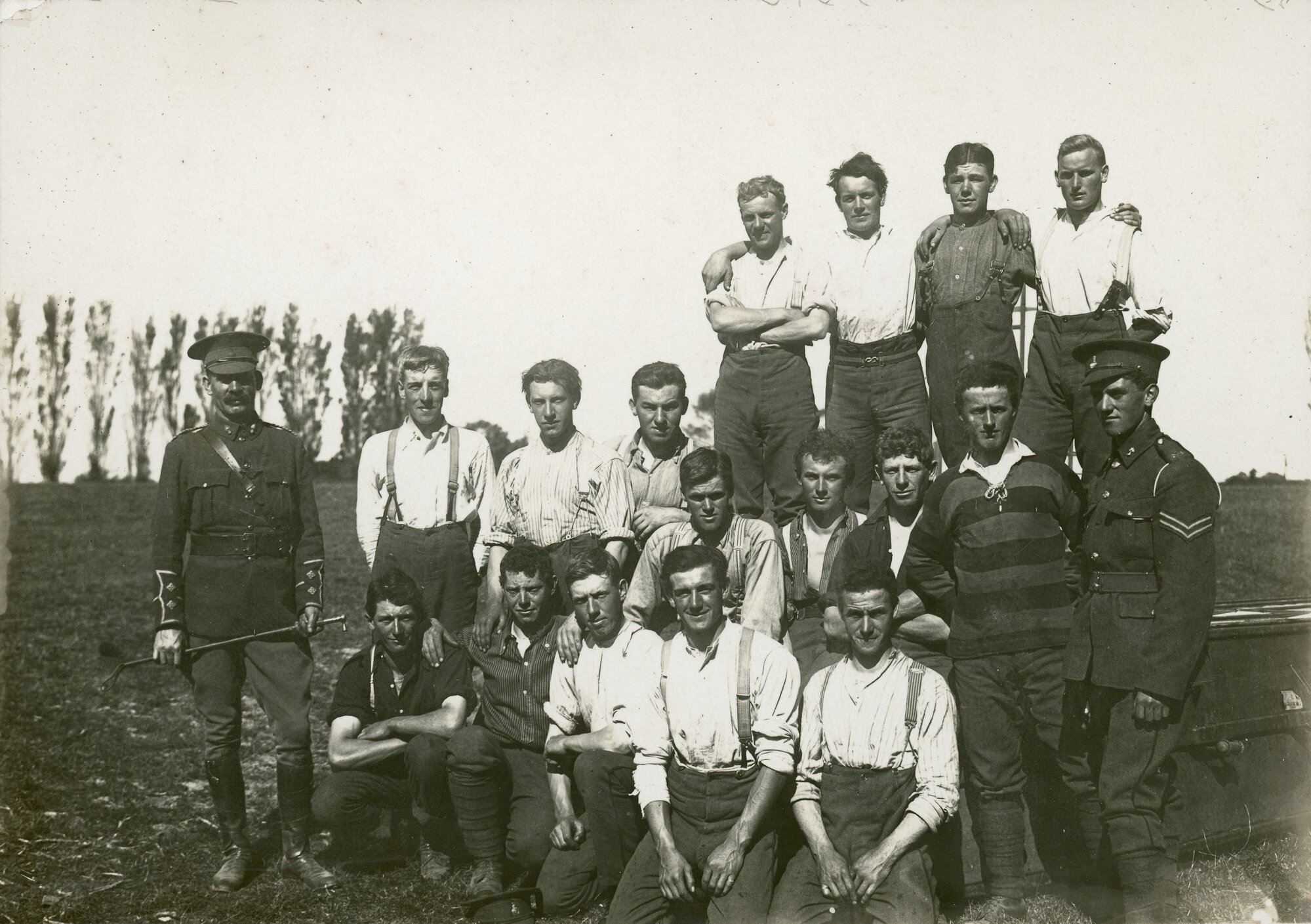 Two soldiers with 16 young men in civilian clothing, c. 1914