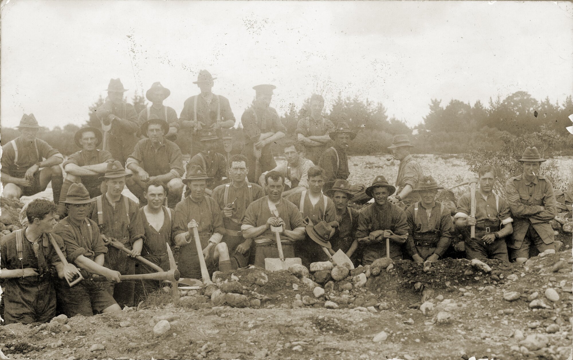 Soldiers with picks &amp; shovels standing in trench.
