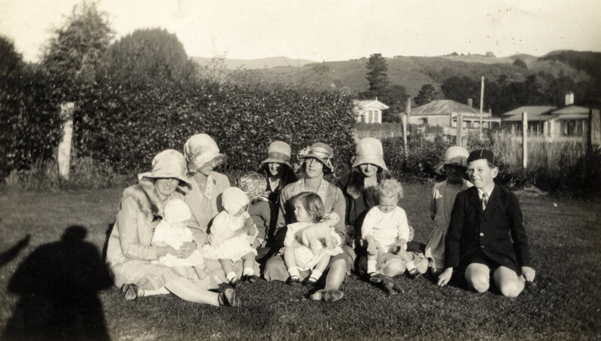 Women and Children sitting on grass; Circa 1931