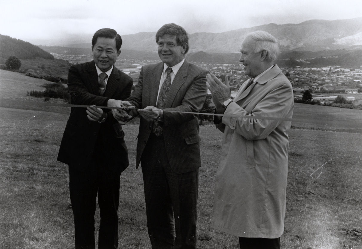 Craig's Flat ground-breaking; Mayor Rex Kirton cuts the ribbon, assisted by Dr Wu; Dennis Ryan applauds.