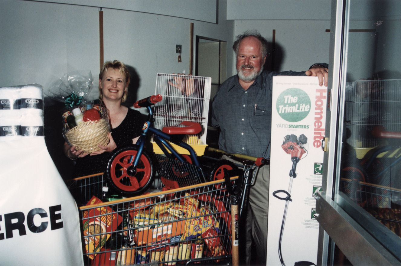 Retailers' Association; Sue Trueman, Lance Cottam with prizes for "Fill Ya Stocking Festival" draw.
