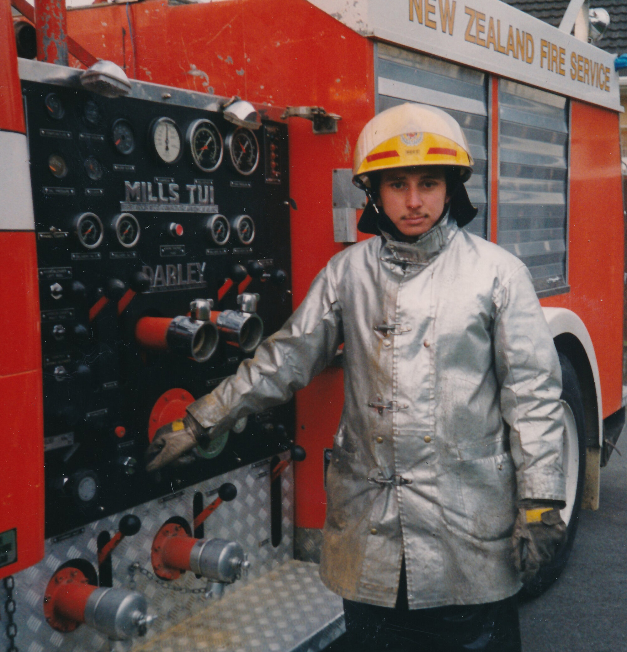 Silverstream Volunteer Fire Brigade; Firefighter Tim Rees standing next to a 1990s pump operators station