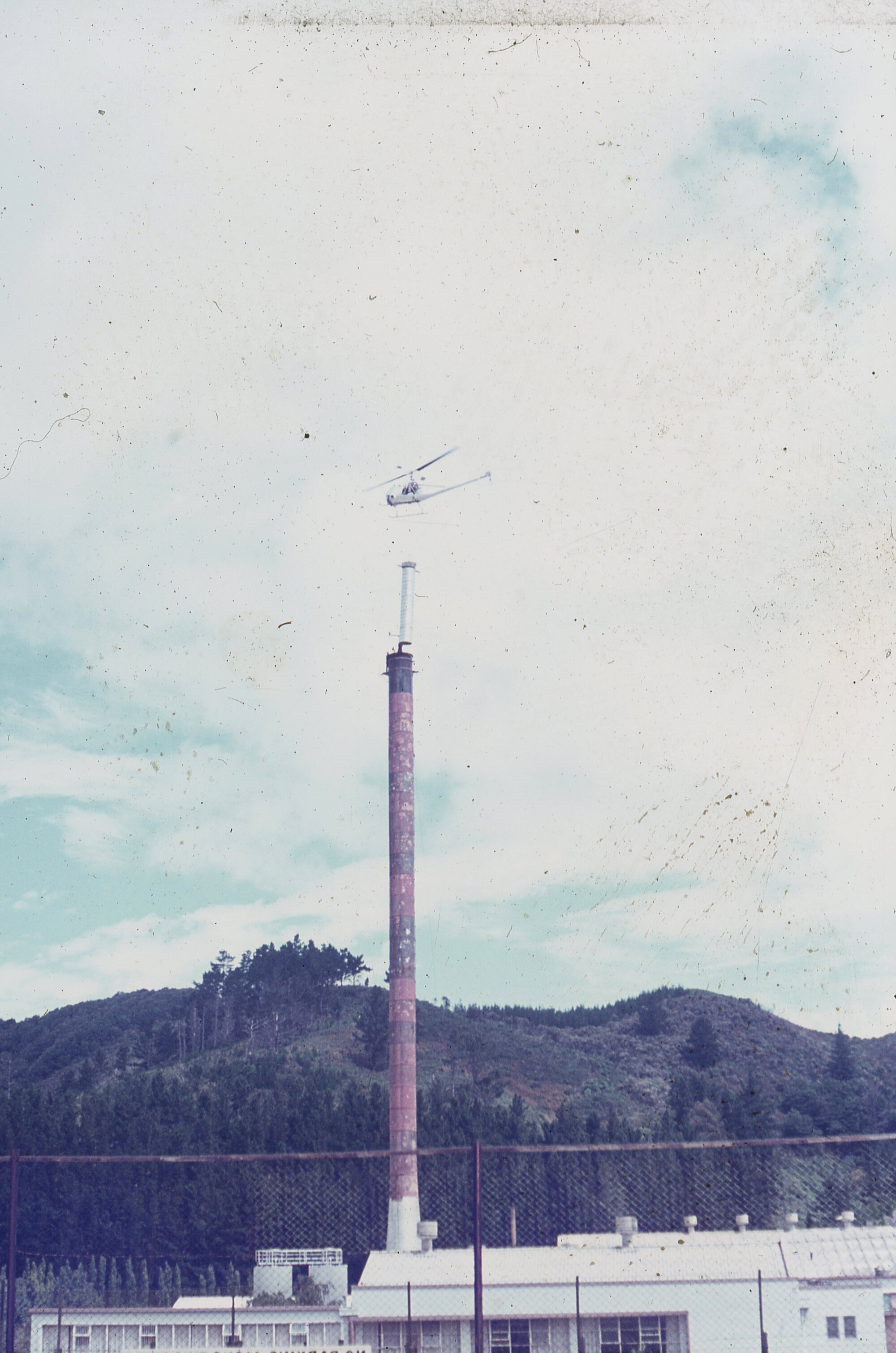 Chimney being helicoptered into Dunlops; ca. 1972-73