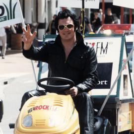 Victim Support fund-raiser; Constable Brian Childs drives ride-on mower up Main Street. 