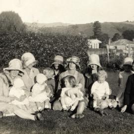 Women and Children sitting on grass; Circa 1931