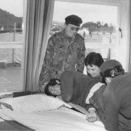 Civil Defence simulated-earthquake exercise; with Army and Red Cross; moving casualty from stretcher to bed, Fraser Crescent School.