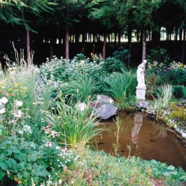 Efil Doog Garden of Art to open in 1995; perennials surround a pond.